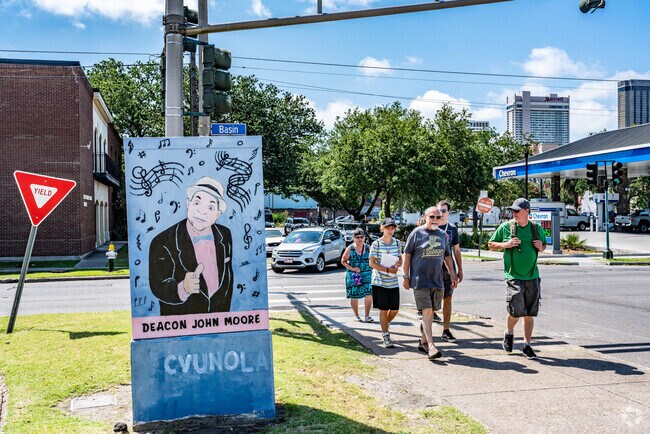 People walking beside a mural of Deacon John Moore in the Iberville neighborhood.