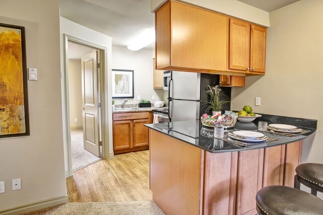 Colonial Square bar and barstools facing into the kitchen that includes a refrigerator, oven, stove, and microwave