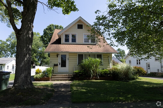 A cheery yellow home basks in the sun & mature trees offer shade to it's yard, in Newton Falls.