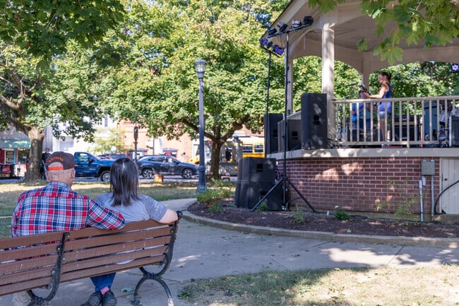 A shaded park bench offers relief from the sun, as Lodi residents enjoy music from the Central Park gazebo.