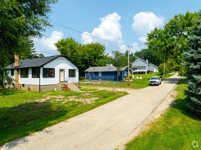 A tree-lined street in Como, Wisconsin, winds past cracked pavement and charming lakeside homes.