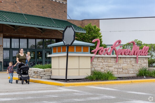 Families stroll past the entrance to Fox River Mall, a shopping hub near Fox Crossing.