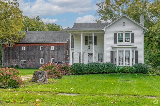 A beautiful farmhouse sits near downtown Kaneville with a vintage barn in the foreground.