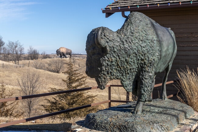 A bronze bison at the North American Bison Discovery Center looks toward its larger sibling.