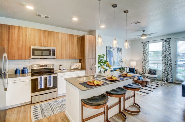 Kitchens feature oak upper and white lower cabinetry, grey quartz countertops, white subway tile backsplash, kitchen island or breakfast bar, and luxury vinyl plank flooring