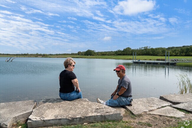 A couple sits on the waters edge enjoying the beautiful scenery at Whalon Lake.