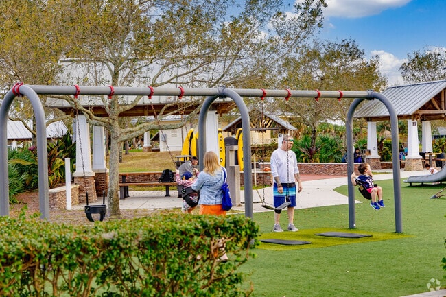 Families from Baywinds enjoy playground time at Commons Park with shaded swing sets.