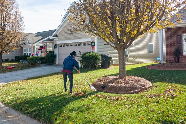 A person sweeps away autumn leaves in City View.