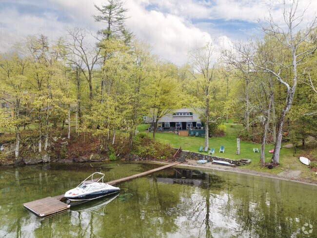 A Craftsman-style home sits in the distance with its own private dock and boat.