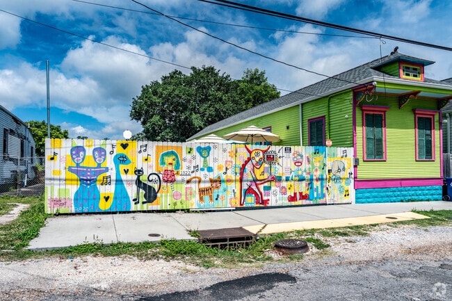 A brightly colored home features a mural painted on a fence in the Saint Roch neighborhood.