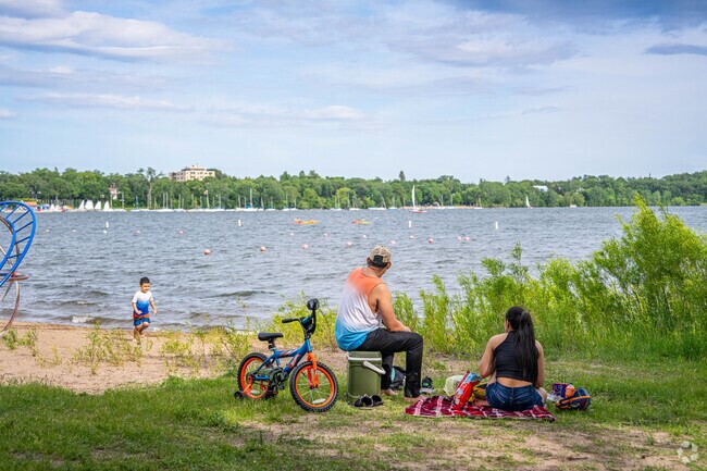 Parents and their child enjoy the beach at Bde Maka Ska.