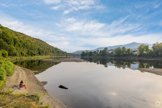 Two friends sit on the bank of the Connecticut River on a warm day in the town of Cornish.