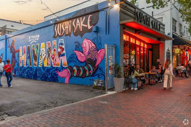 A colorful mural and people dining at Sushi Sake in Calle Ocho.