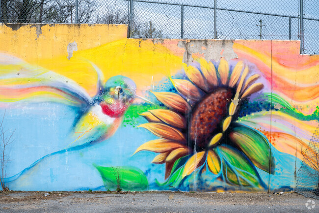 A mural depicting a hummingbird and sunflower on a concrete wall in Capitol Heights.