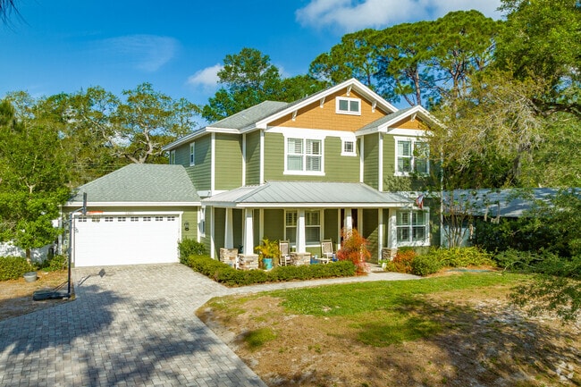 A colorful cottage style, two-story house is surrounded by trees in Safety Harbor.