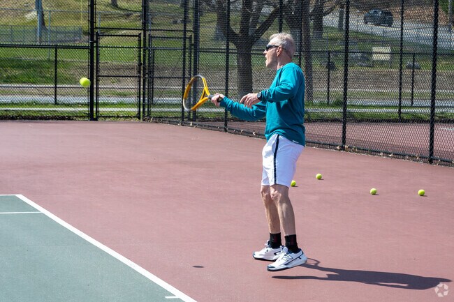 A man hits the tennis ball at Quinsigamond State Park.