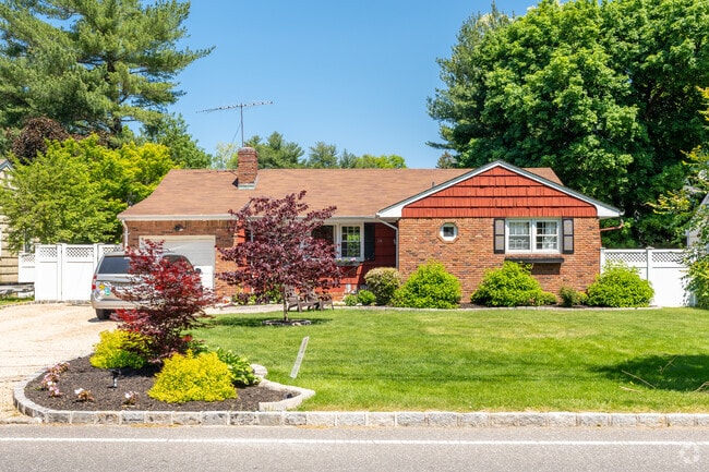 Cross-gabled ranch-style home with attached garage is in Sea Cliff.
