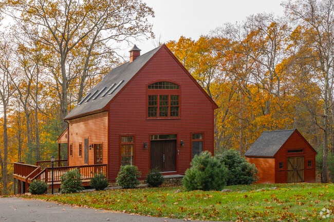 A home converted from a barn is nestled amidst vibrant fall foliage.