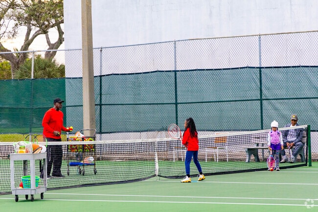 A tennis coach teaches young Roosevelt Estates children the game at Gaines Park.