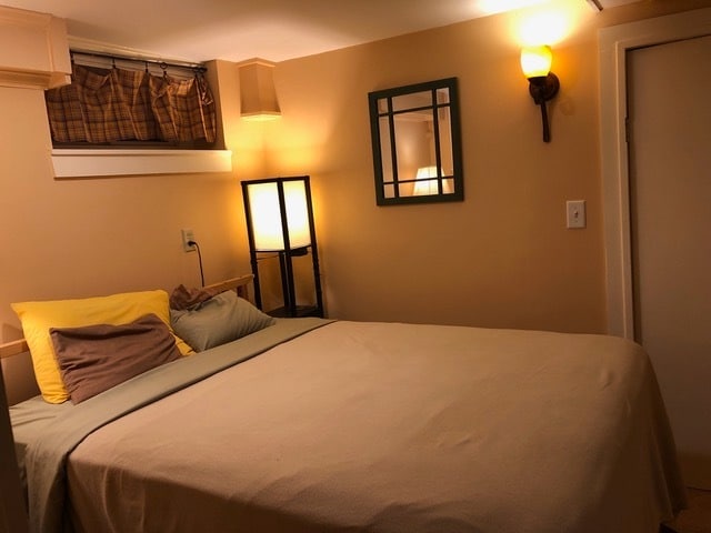 Cozy bedroom has small dresser, secretary desk, and two night tables
