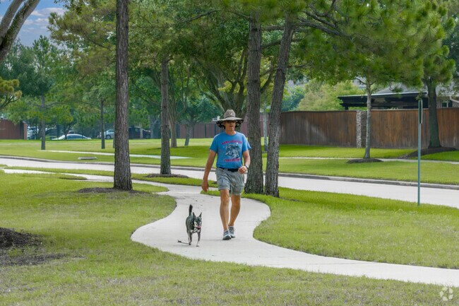 A man walks his dog along a sidewalk at Southern Trails Park.