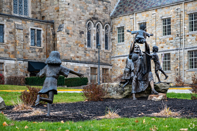 A statue on the grounds of a large stone built church in the neighborhood of Washington.