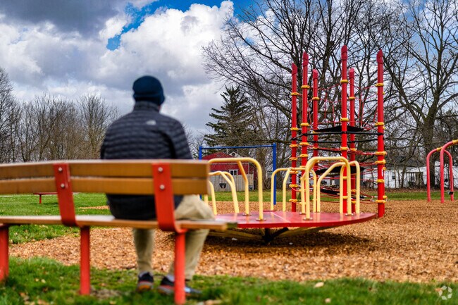 A man watches his child play on the playground at Hull Court Park.