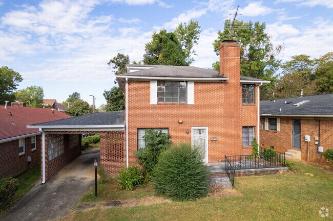 A large brick 2-story home with a large bush in the front yard.