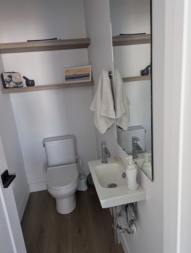 Half bathroom featuring wood finished floors and toilet