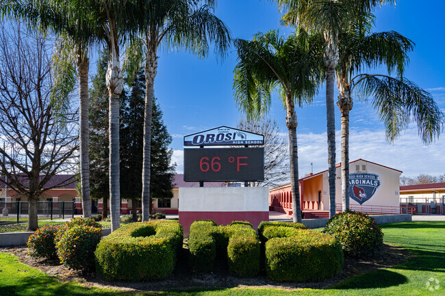 The front marquee of Orosi High School is surrounded by palm trees and hedges.