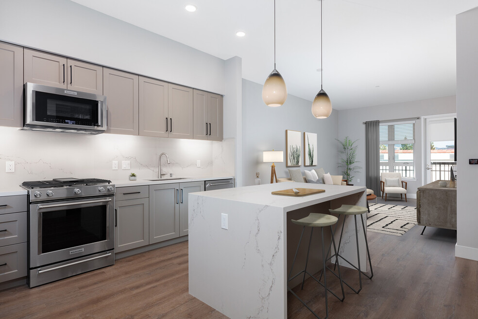 Signature Collection kitchen with upgraded stainless steel appliances, grey cabinetry, white marble countertops and backsplash, and hard surface flooring