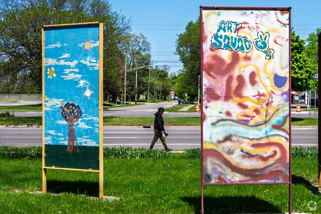 A woman walks around Farwell Park, passing by community art murals near Nortown.
