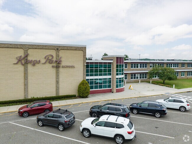 The Kings Park High School's main entrance has a parking lot in the front of the building.