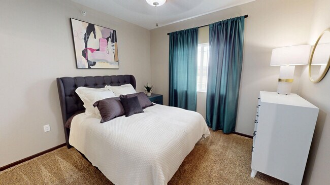 The primary bedroom in The Hub floor plan features lush carpet, a large window, and en suite bathroom.
