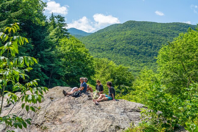 A family enjoys the view from a rocky perch at the Bolton Potholes overlooking Bolton Valley.