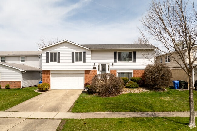 A split-level home in Mount Shire with brick at the base and white siding above.