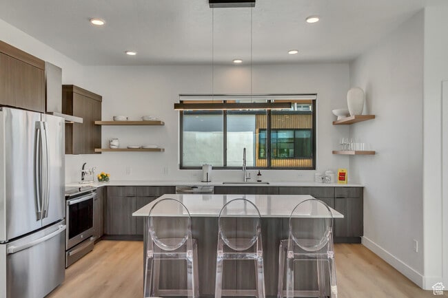 Kitchen with appliances with stainless steel finishes, open shelves, wall chimney exhaust hood, mode