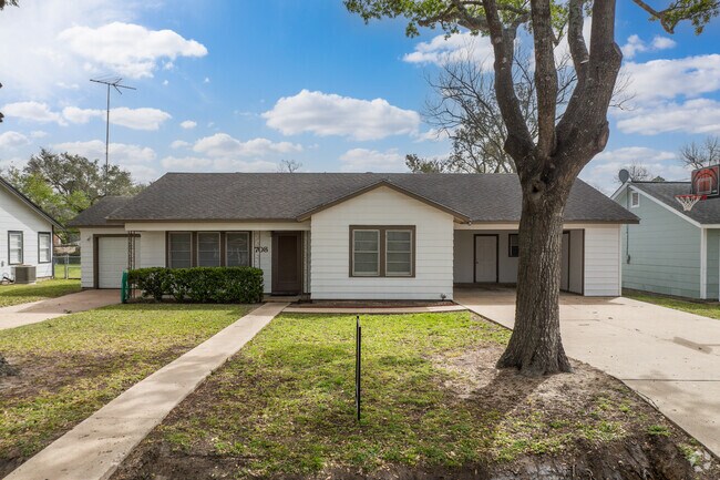 A single-family ranch home sits under the shade of a mature oak tree in El Campo.