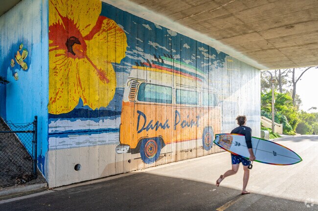 A surfer runs by the mural at Salt Creek Beach Bluff Park.