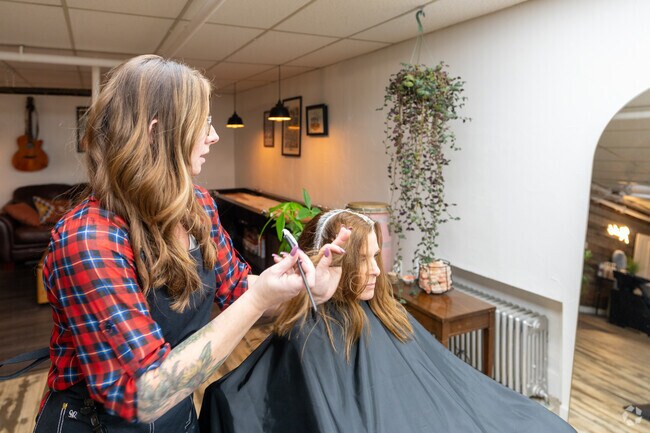 A hairstylist brushes a client's hair with dye at Rooted Hair Co near Brookline.