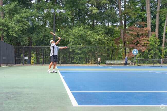 Tennis players get ready to serve their doubles match at Longwood Park.