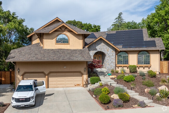 Custom contemporary home in Pierce Ranch features arched stone entry and lush drought-tolerant garden.
