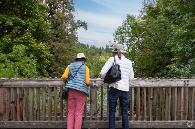 Two women peak over at Oswego Creek from the Old River Rd Bridge in Hallinan.