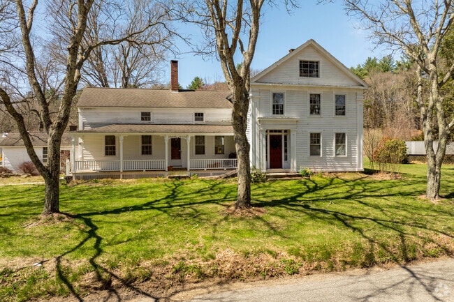 A farmhouse style home in Chaplin has an expansive yard dotted with trees.