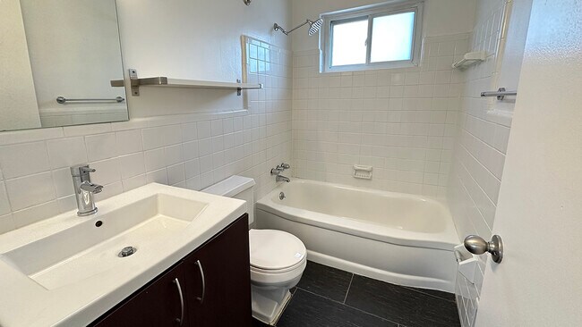 Subway tile bath surround, black tile flooring, farmer's sink, nickel hardware, rainfall showerhead and a window, too.