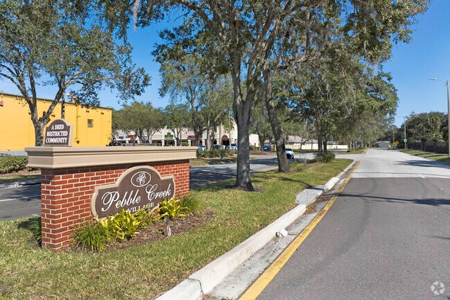 The Pebble Creek Village monument sign welcomes residents with seasonal flowers and decor.