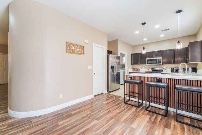 Kitchen featuring appliances with stainless steel finishes, decorative light fixtures, light wood-st