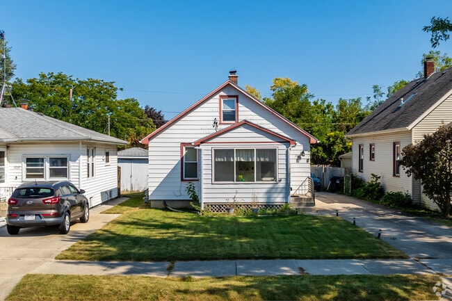 Located in Humble Park is a modest bungalow home with white siding and small front yard.