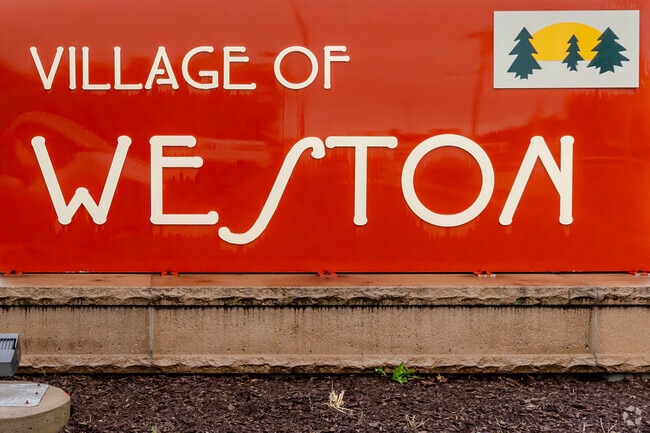 A bold red welcome sign greets visitors as they enter the Village of Weston.