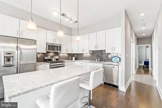 Open kitchen featuring gas range, stainless steel appliances, built-in microwave, marble countertops